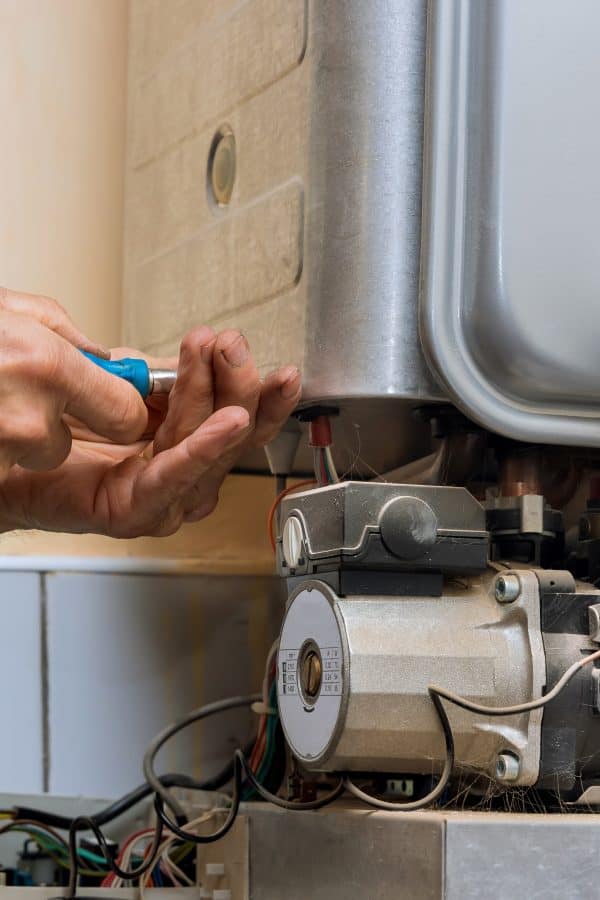 Technician worker looking inside gas heater trying to fix the problem Technician worker looking inside gas heater trying to fix the problem